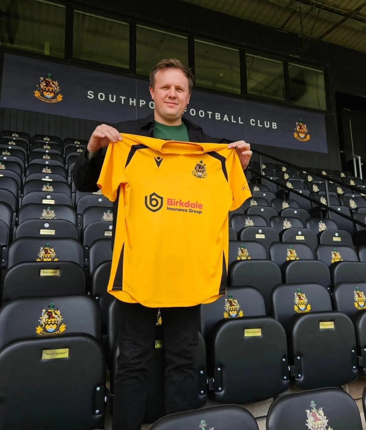 Elliott Horan holding a Southport FC shirt featuring its sponsor